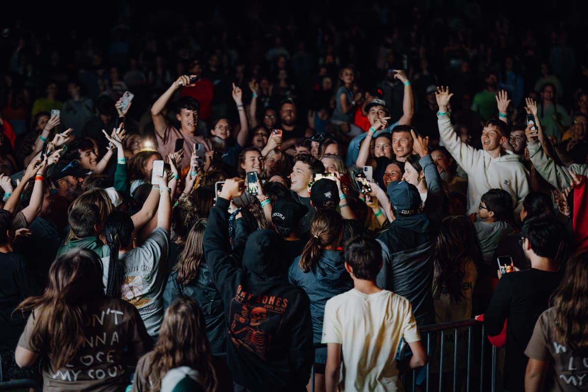 Crowd near the barricade with hands and phones in the air during a set