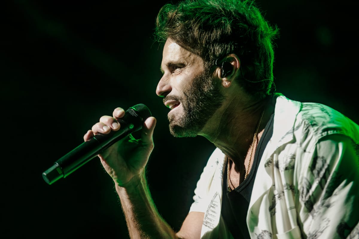 Vocalist singing under green stage light, microphone in hand