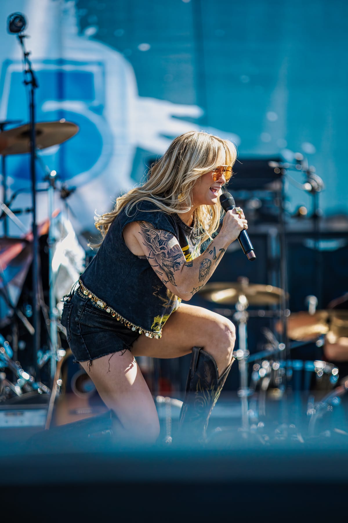 Singer crouched at the edge of the stage mid-performance