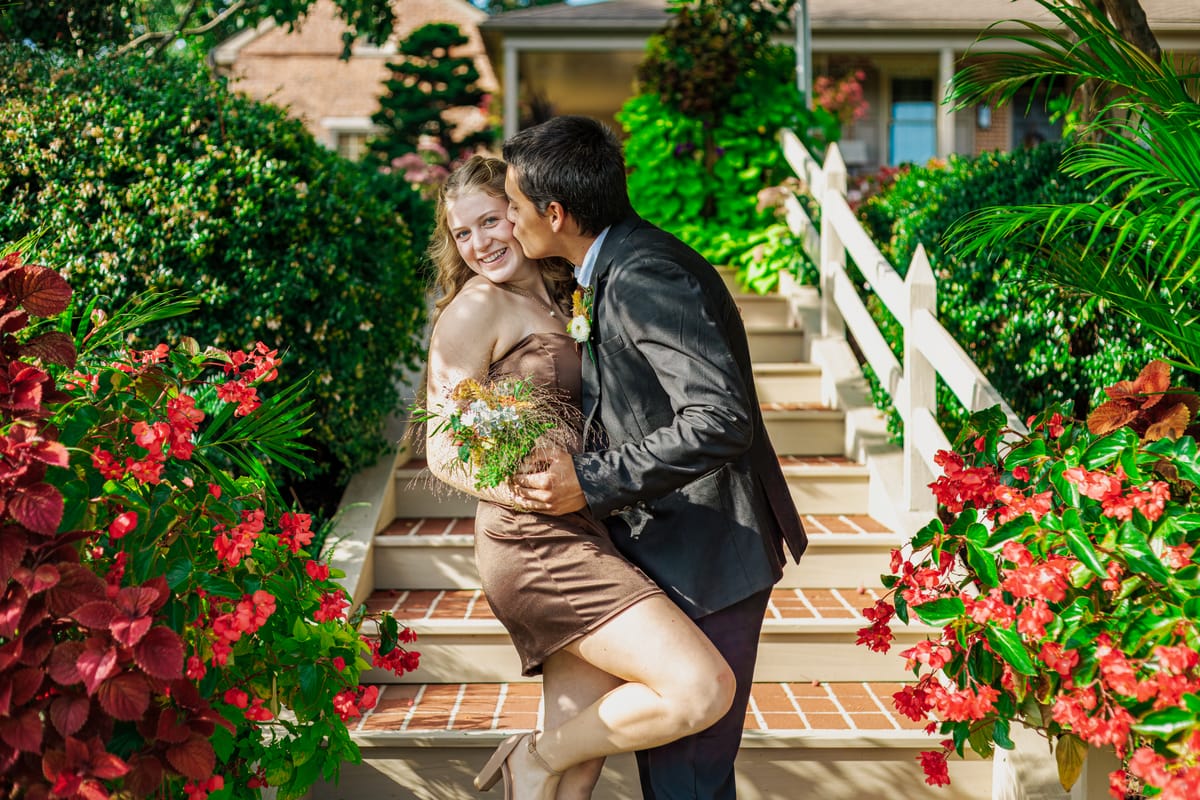 Couple sharing a kiss on a flower-lined staircase