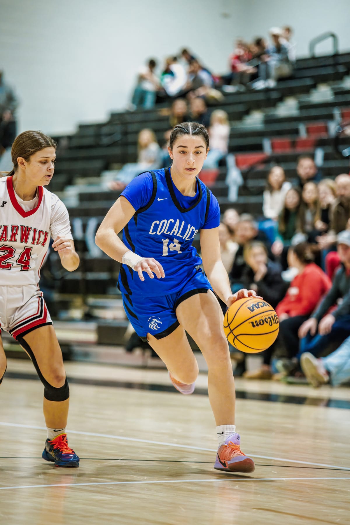 Basketball guard driving the ball upcourt past a defender