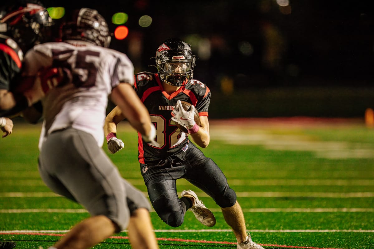 Ball carrier cutting back upfield past a defender during a night game