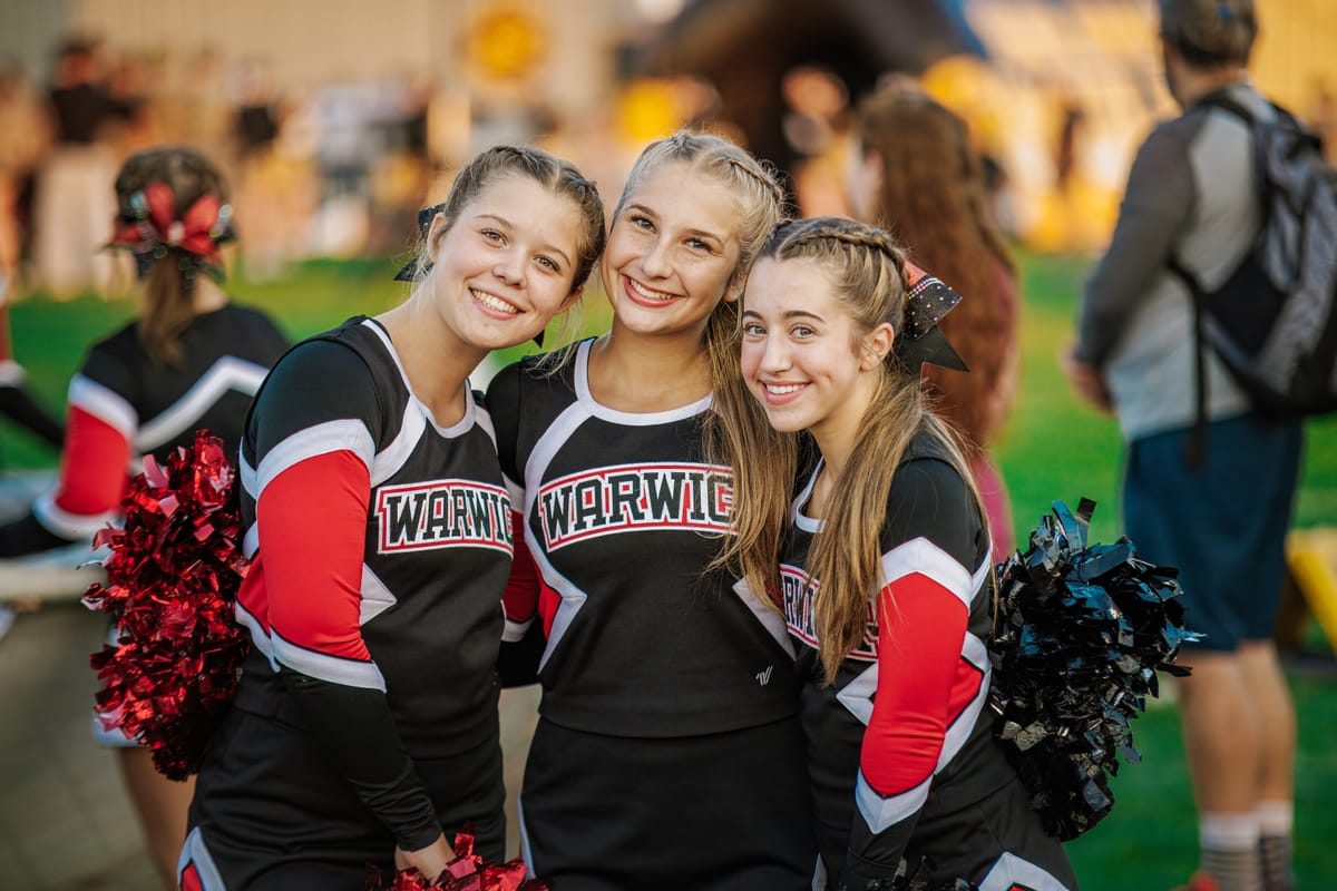 Three cheerleaders posing on the sideline in team colors