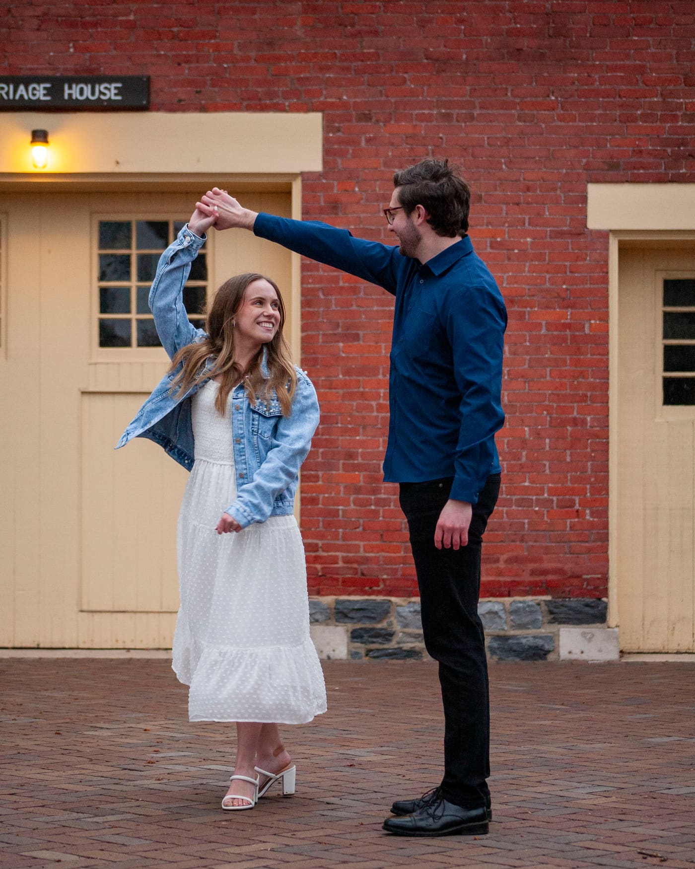 Couple dancing as the groom twirls the bride outside a carriage house