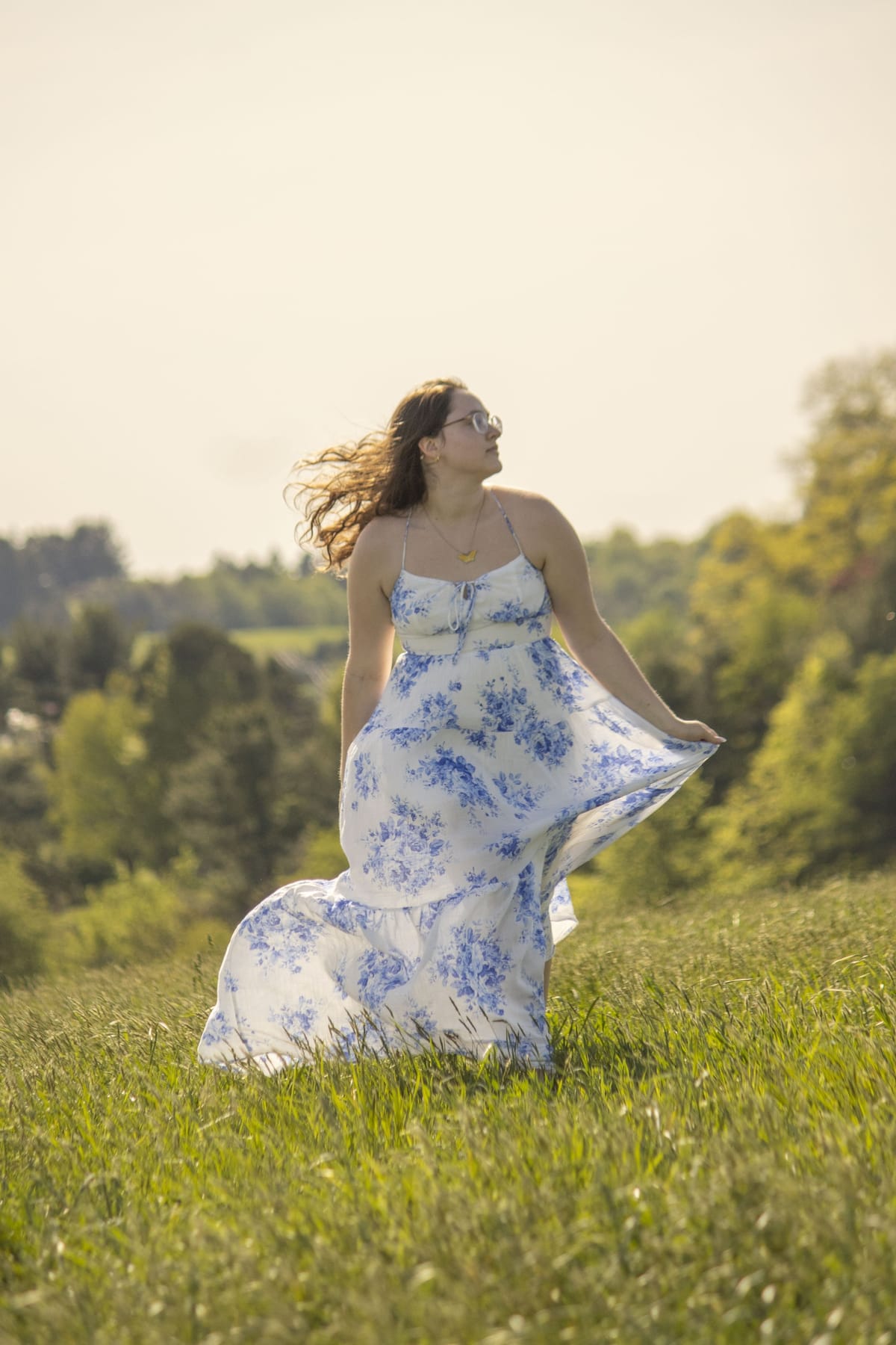Bride in a blue floral dress walking through a windswept summer field